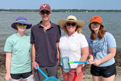 Family standing on a beach with hats, sunglasses, and crabbing gear.