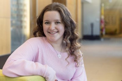 Woman in a pink sweater sitting on a green chair.