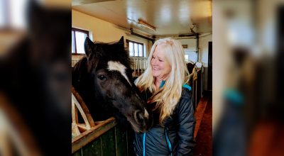 Woman standing with a pony in the stables.