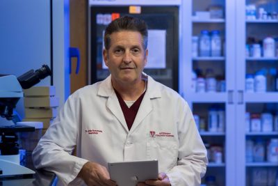 John Rossmeisl (at center) posing in a lab holding an iPad.