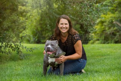 Erin Phoenix poses in the grass with a dog.